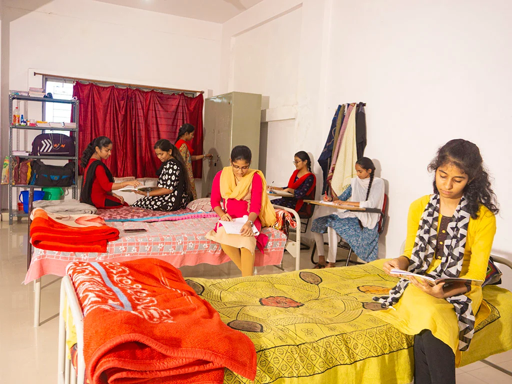 Neatly arranged beds in hostel dormitory with personal study tables